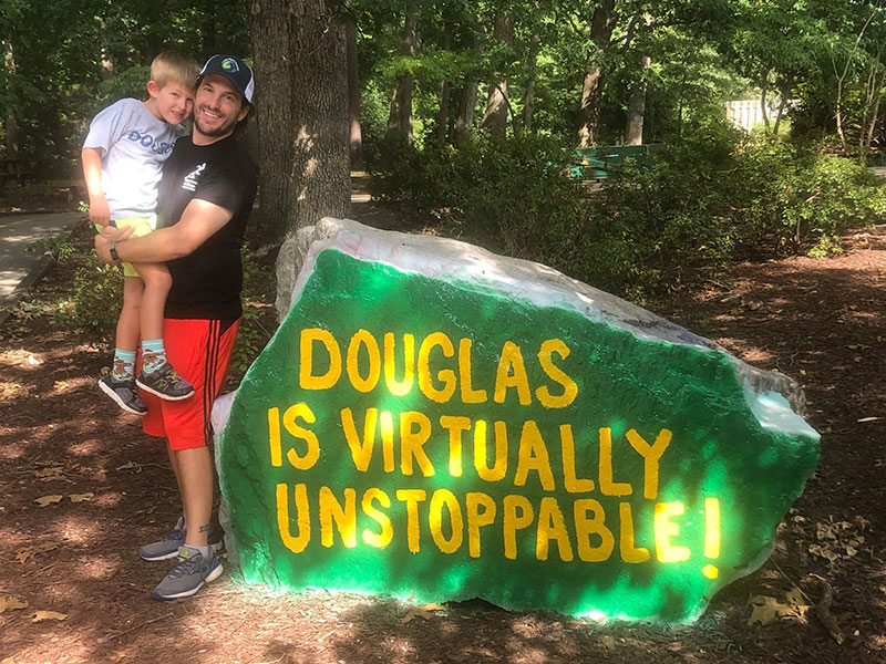 man holding child by school spirit rock
